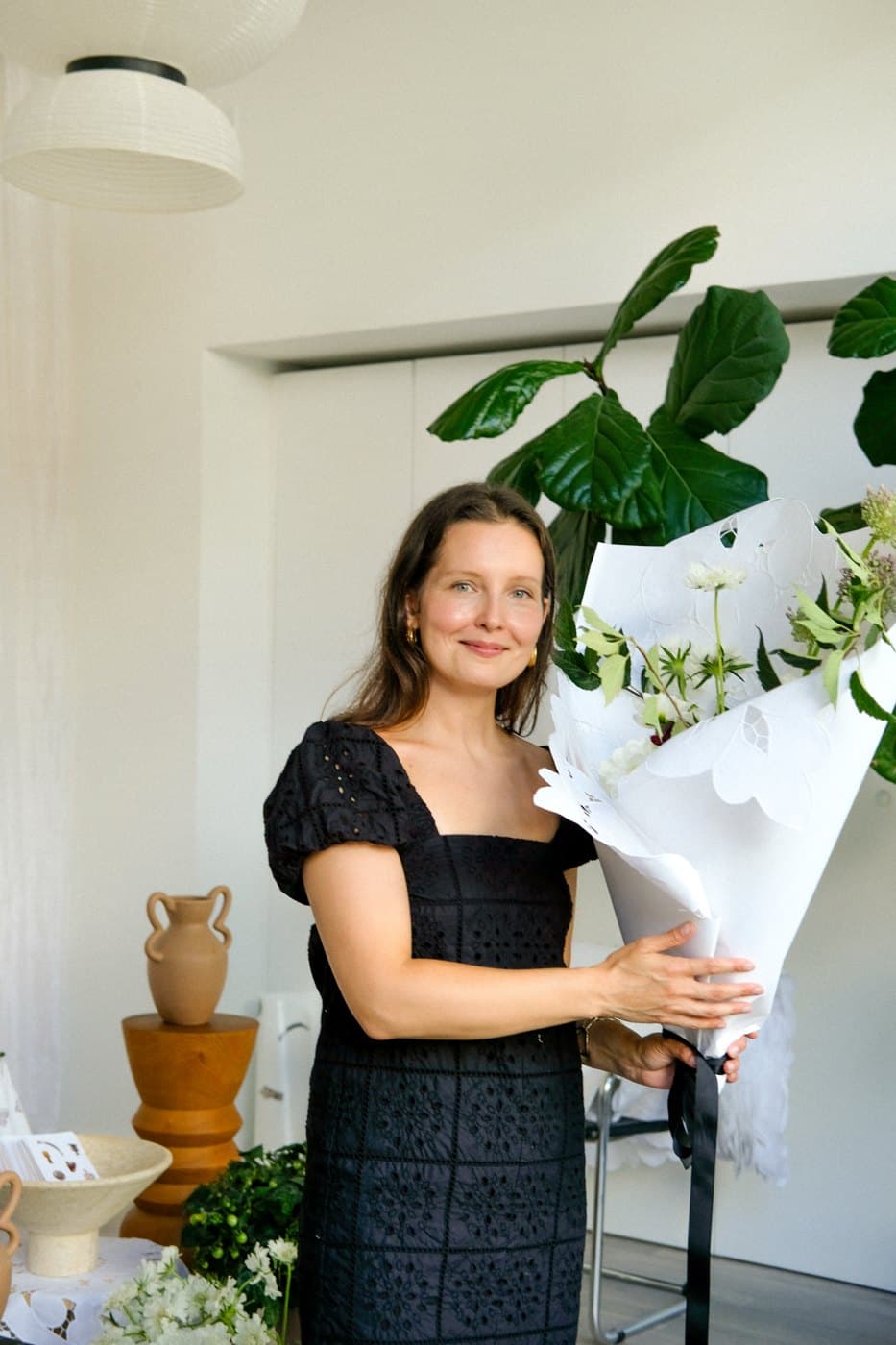 Bloomiér florist holding a white-wrapped bouquet at a pop-up flower shop in a Vancouver office